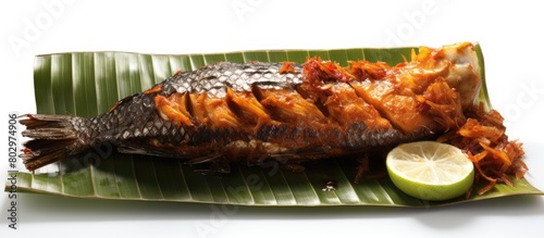 A burned fish with sour sauce spicy flavor minced garlic placed on banana leaves and isolated on a white background with copy space image