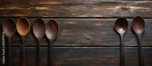 A dark wooden table showcases the rustic charm of old wooden spoons offering a textured backdrop for copy space images