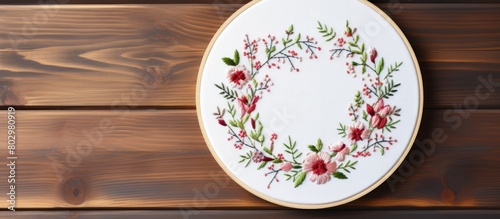 A cross stitch kit with white cotton fabric and an embroidery hoop is showcased on a wooden background offering a copy space for customization