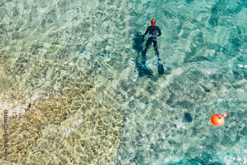  Drone view of spearfisherman in wetsuit with buoy looking for a fish