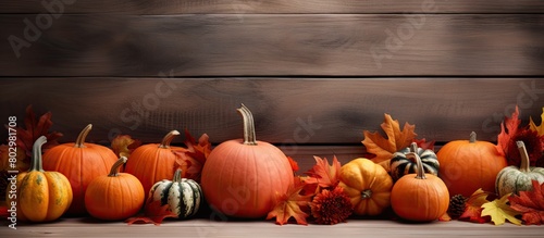 A copy space image featuring autumn leaves and pumpkins arranged on an old wooden background