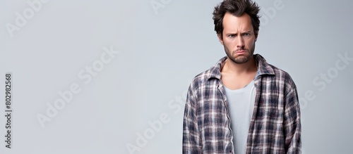 A displeased young man in pajamas with a handsome face stands against a white background He wears a frown appearing on the verge of tears expressing discontent and unhappiness due to unfulfilled goal