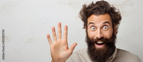 A bearded man enthusiastically announces a discounts sale with copy space image on a beige background while greeting someone hello photo