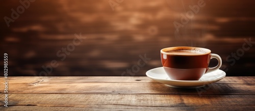 A cup of coffee placed on a wooden table providing ample empty space for other elements in the image