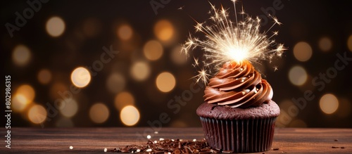 A delicious chocolate cupcake is displayed on a wooden table adorned with a sparkling sparkler creating an eye catching copy space image photo