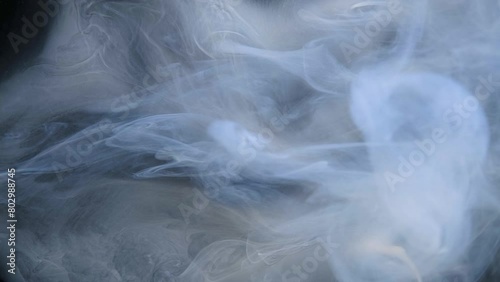 Wisps of smoke intertwine gracefully against a dark backdrop. (ID: 802988745)