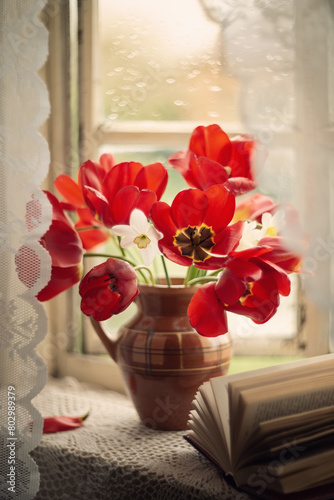Still-life. Photo of a bouquet of red tulips with daffodils near the window.