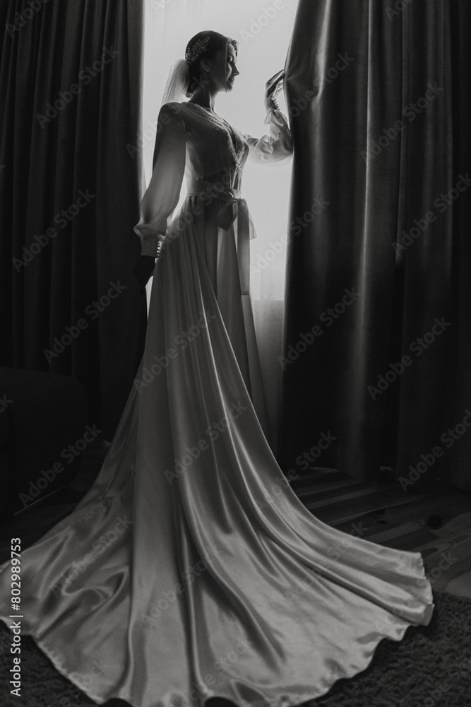 A woman in a wedding dress stands in front of a curtain. The dress is long and flowing, and the woman is wearing a veil. The image has a moody and dramatic feel A woman in a wedding dress stands in front of a curtain. The dress is long and flowing, and the woman is wearing a veil. The image has a moody and dramatic feel