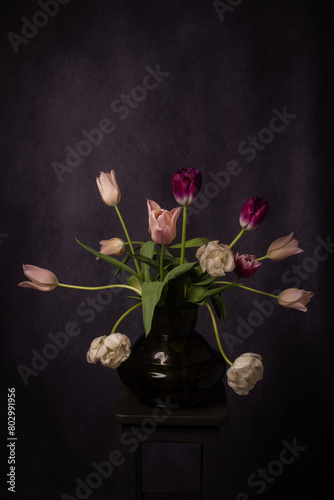 classic dark and painterly renaissance photo of pink and white tulips in glass vase  photo