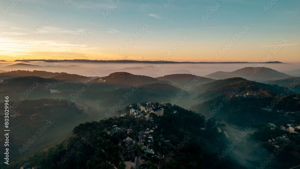 An aerial view of Da Lat city nestled among green hills, with a lake in the foreground.