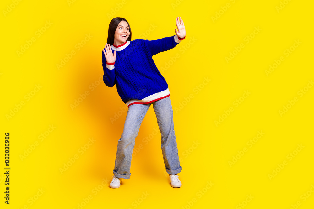 Full length photo of pretty teen girl dancing have fun good mood wear trendy knitwear blue outfit isolated on yellow color background Full length photo of pretty teen girl dancing have fun good mood wear trendy knitwear blue outfit isolated on yellow color background