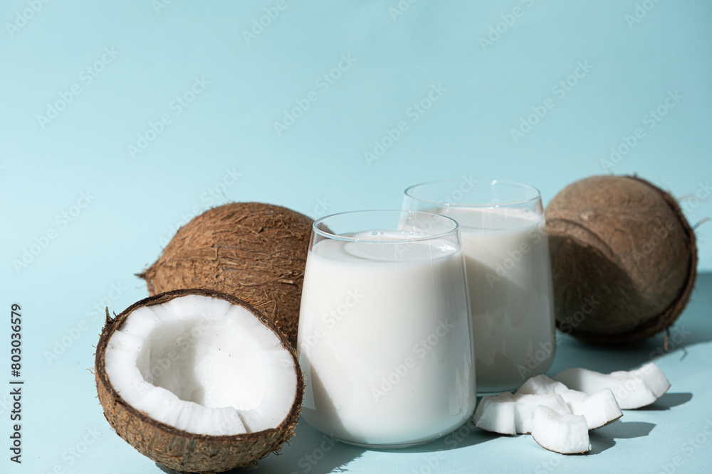 Coconut milk in a glasses among coconuts on a blue background Coconut milk in a glasses among coconuts on a blue background