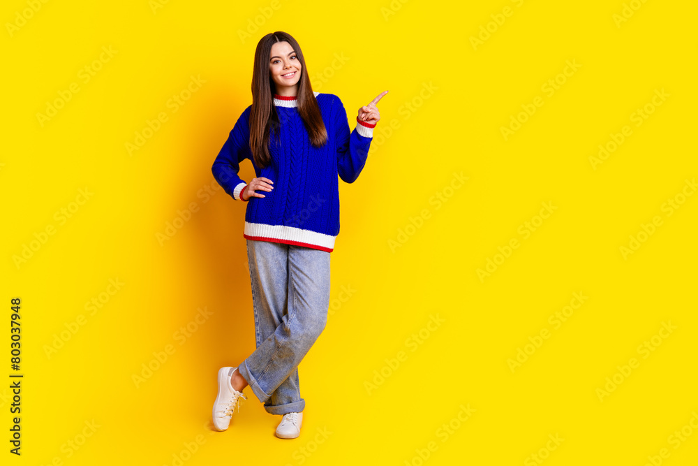 Full length photo of pretty teen girl point empty space wear trendy knitwear blue outfit isolated on yellow color background Full length photo of pretty teen girl point empty space wear trendy knitwear blue outfit isolated on yellow color background