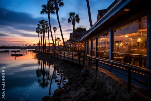 Sunset at the Ocean Marina Cafe  with Sailboats Docked Nearby and a Lighthouse in the Distance