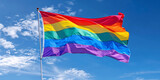 Pride rainbow lgbt gay flag being waved in the breeze on blue sky