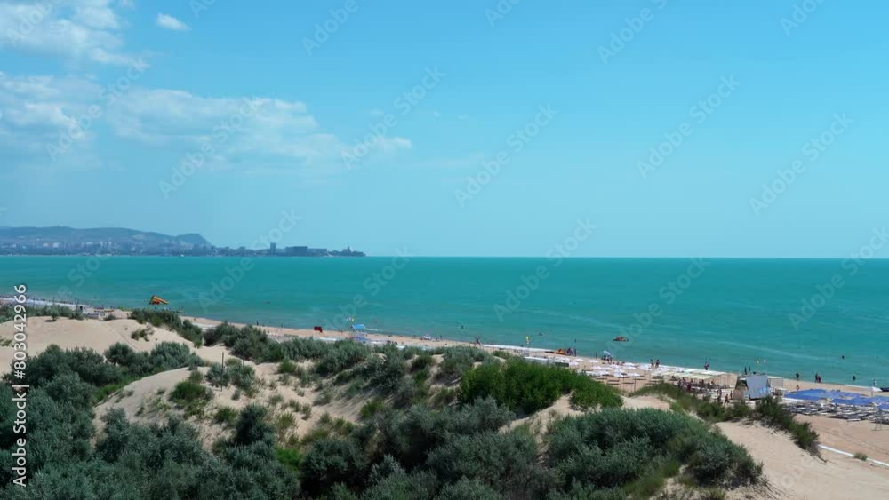 View of sand beach with dunes and blue sea with swimming and relaxing people in summer day. Travel, tourism, vacation. Sea landscape View of sand beach with dunes and blue sea with swimming and relaxing people in summer day. Travel, tourism, vacation. Sea landscape