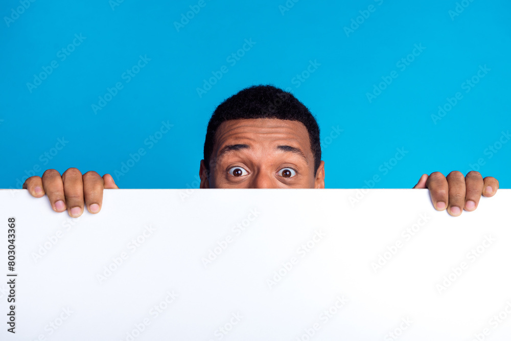 Photo of nice young man hide face behind empty space blank isolated on blue color background