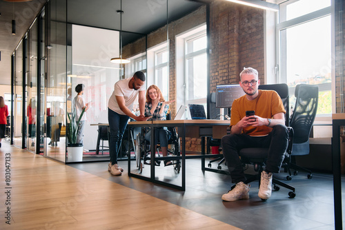 A diverse group of business professionals collaborates in a modern startup coworking center, utilizing a mix of paper-based and technological tools such as mobile phones and computers 