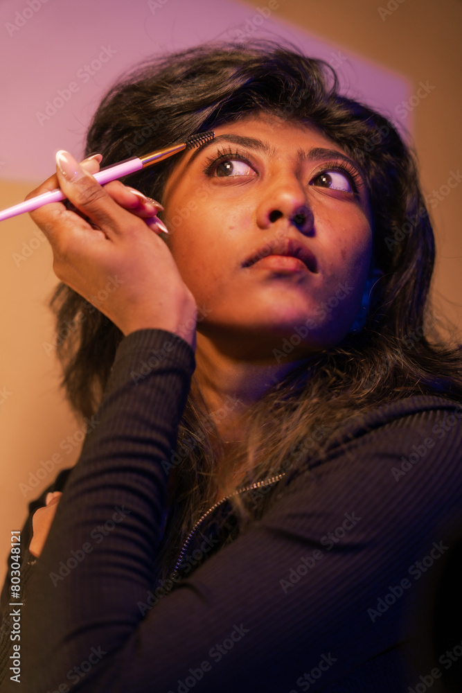 Obraz premium A woman is applying makeup with a brush