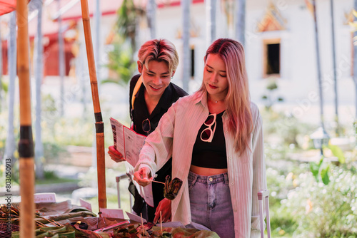 asian traveler lover trying street food at market on holiday. young teenage tourist lover buy local food from local shop. female and male tourist testing chaingmai food of thailand while traveling photo