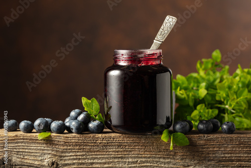 Jar of blueberry jam with fresh berries on an old wooden table. © Igor Normann