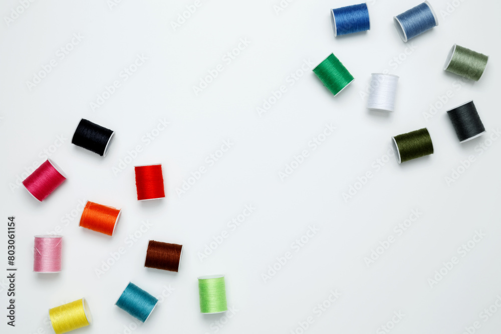 Multicolored sewing threads on white background. Top view, copy space