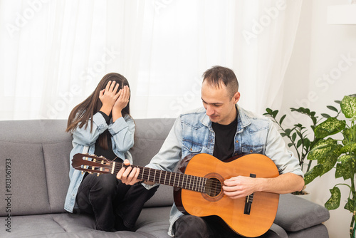 A father teaching his daughter how to play guitar.