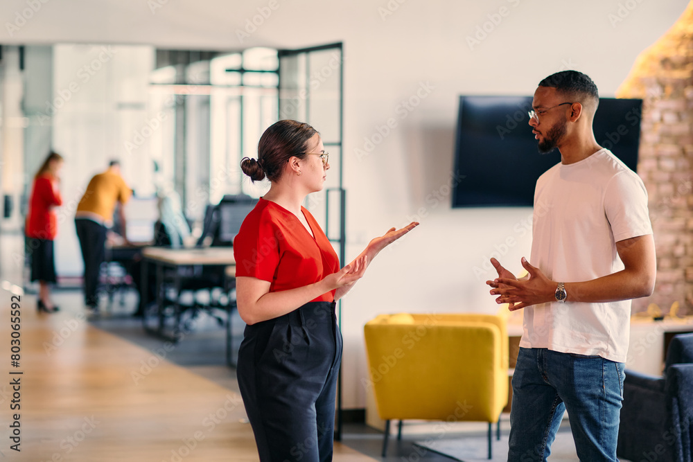 Young business colleagues, including an African American businessman, engage in a conversation about business issues in the hallway of a modern startup coworking center, exemplifying dynamic problem Young business colleagues, including an African American businessman, engage in a conversation about business issues in the hallway of a modern startup coworking center, exemplifying dynamic problem