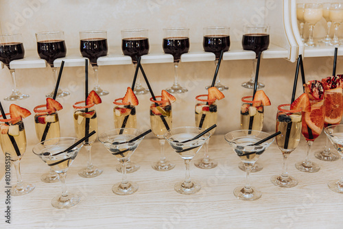 A row of wine glasses with straws in them and fruit garnishes