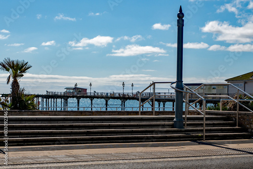 Seaside pier with amusements with blue sky and sunshine. Sandy beach holiday resort. 