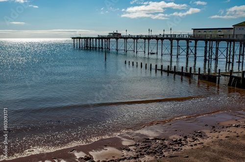 Seaside pier with amusements with blue sky and sunshine. Sandy beach holiday resort. 