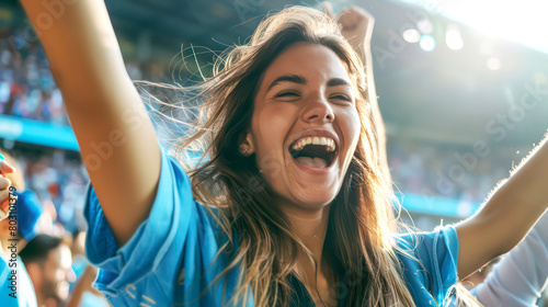 An excited young beautiful woman fan wearing a sport shirt cheered at the football stadium, cheering for their team to win the game. photo