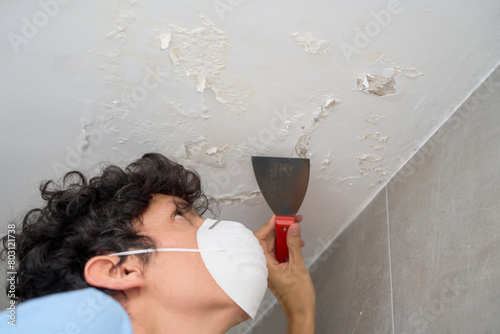Tableau sur toile Young man removing moisture and saltpeter from wall and ceiling.