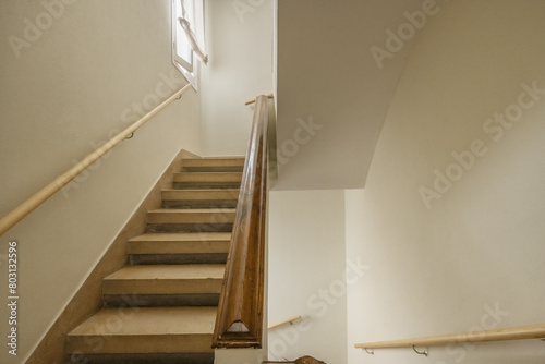 Interior stairs of a single-family home with brick balustrades with wooden handrails and concrete steps