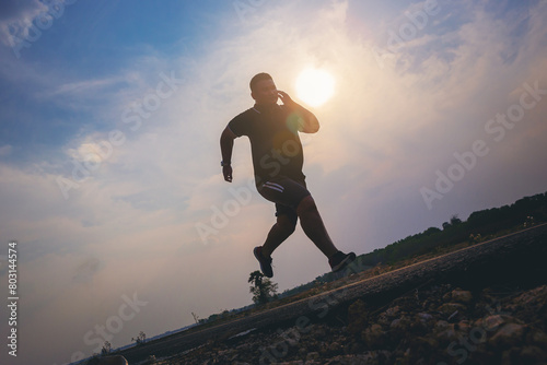 Silhouette of overweight man running sprinting on road. Fat man runner jogging at outdoor workout. Exercise concept for weight control.