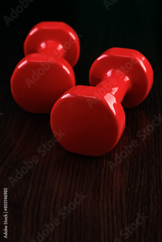 Two red shiny dumbbells lie on a wooden floor. Selective focus. Free space for text. Copyspace. © Yuriy Afonkin