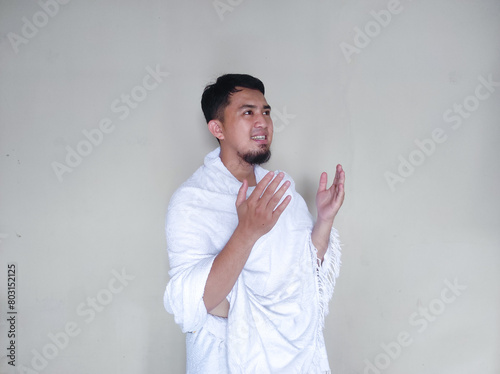 Muslim man praying while standing wearing ihram cloth photo