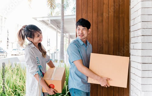 happy woman and man moving in new home. asian adult couple move carton box relocating into new house for bonding relationship. beautiful girlfriend and handsome boyfriend change new place to be home