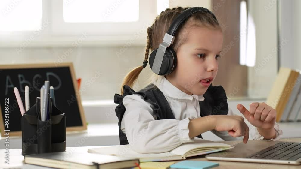 School girl wear headphones have video call , using laptop School girl wear headphones have video call , using laptop