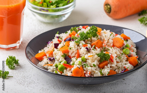 Colorful and nutritious vegan rice salad with a glass of carrot juice photo
