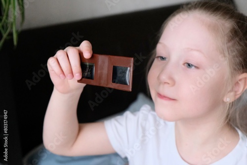 A child is watching slides through a slide show. Retro, slides. Old plastic stereoscope with stereo card. Outdated 3D viewing device. Children retro toy photo