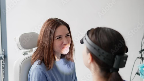 A young brunette girl at an appointment with an ENT specialist closes her mouth because she cannot keep it open for a long time while studying her throat in the ENT office in a modern clinic photo