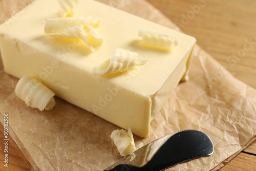 Tasty butter and knife on wooden table, closeup
