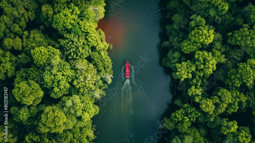An aerial capture of a solitary boat sailing through a narrow river in a serene forest