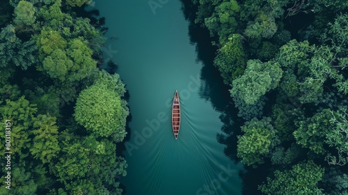 An aerial capture of a solitary boat sailing through a narrow river in a serene forest