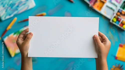 Blank White Paper in s Hand on Colorful Art Studio Background
