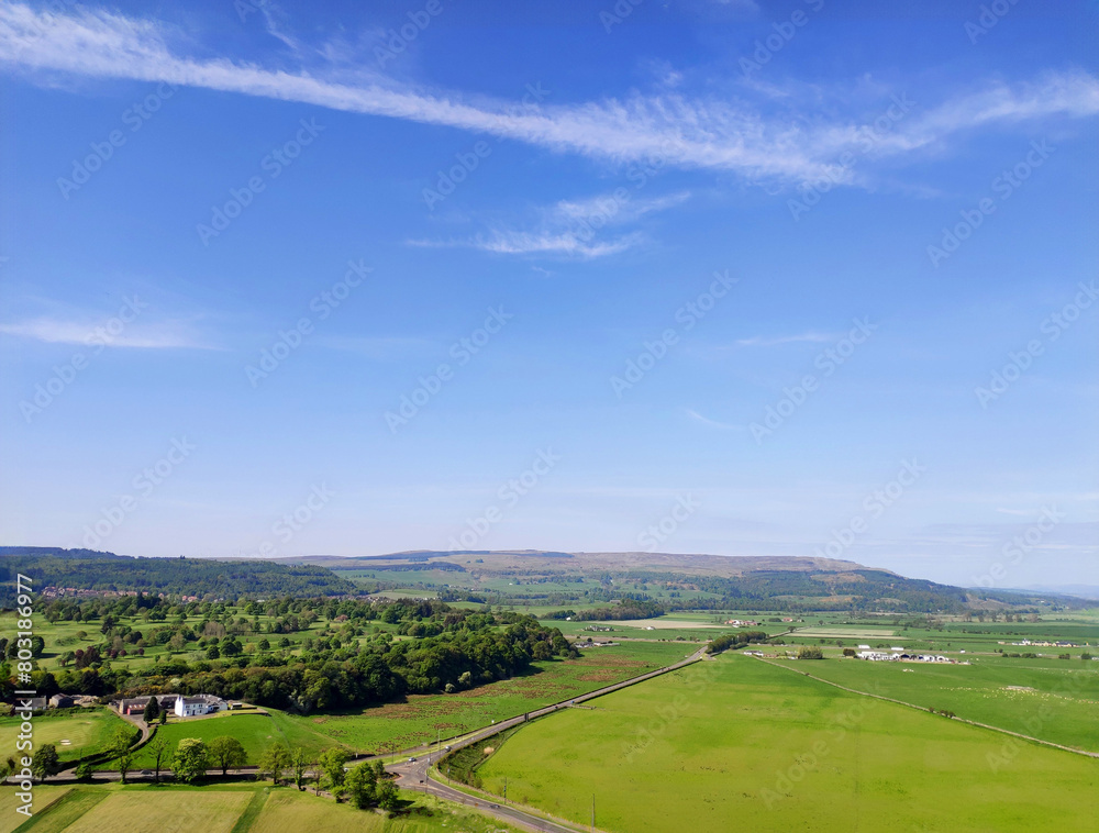 Lawn and mountains in the wild fields of Stirling, Scotland, UK, with blue sky and white clouds