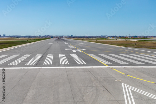 Looking down at airport runway 24 from inside an airplane about to take off on a clear day showing tire marks in the distance