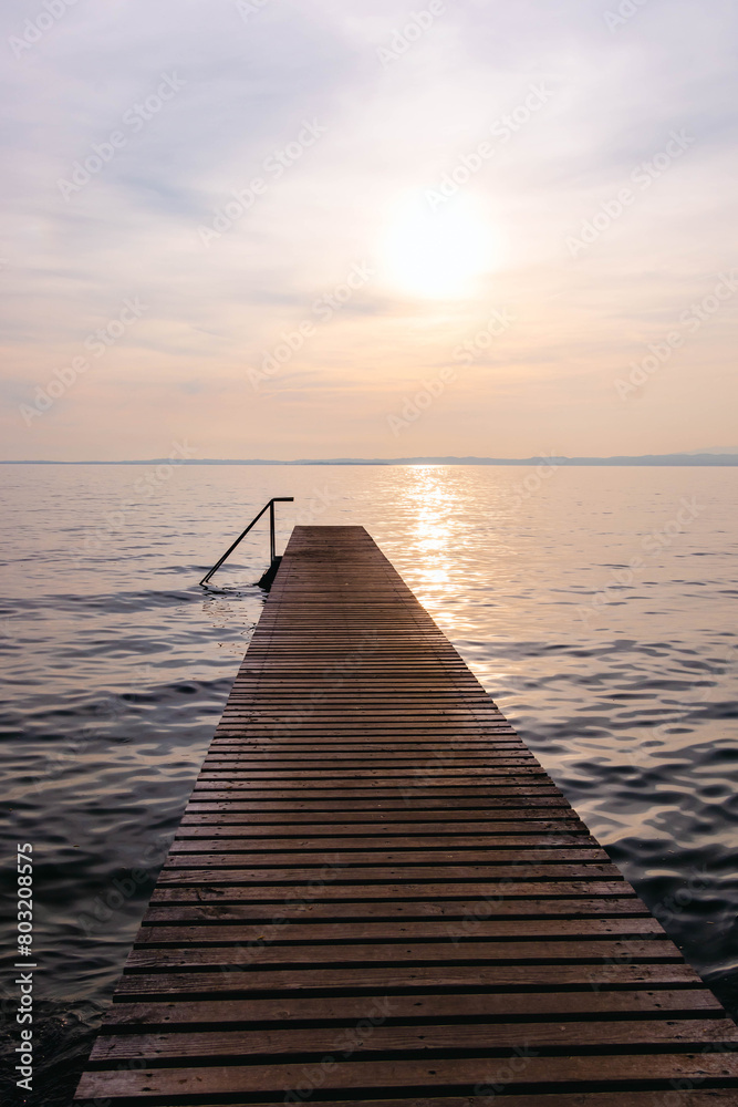Obraz premium Wooden pier at sunset seen from walkway at Cisano, Bardolino, Lake Garda, Italy