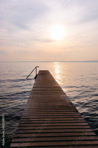 Wooden pier at sunset seen from walkway at Cisano  Bardolino  Lake Garda  Italy